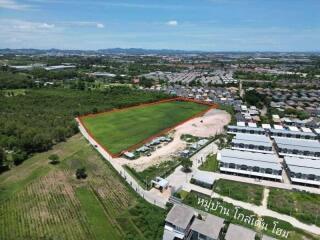 Aerial view of a large green field next to residential buildings