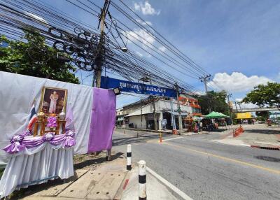 Street view with electrical wires, buildings, and a sidewalk shrine