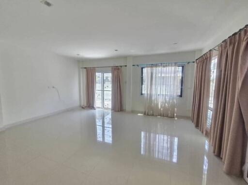 Spacious living room with large windows and tiled floor