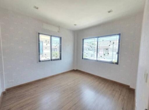 Empty room with two large windows and wooden floor