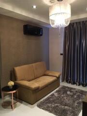 Modern living room with a brown sofa, elegant chandelier, and accent wall.