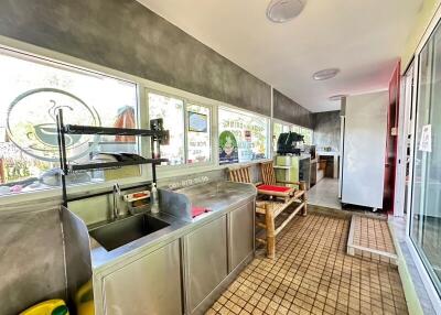 Well-lit kitchen with stainless steel sink and storage shelves