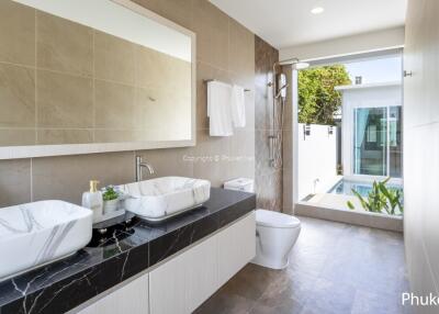 Modern bathroom with double sinks, large mirror, and backyard view