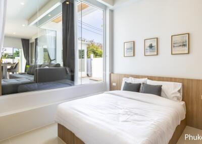 Modern bedroom with large window and framed pictures above the bed