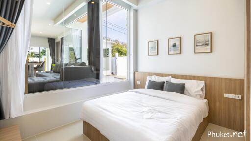 Modern bedroom with large window and framed pictures above the bed