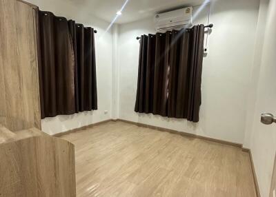 empty bedroom with wood flooring and brown curtains