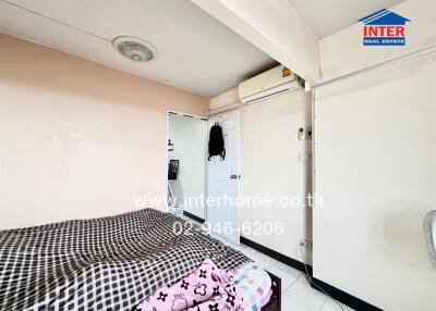 A small bedroom with a bed, air conditioning unit, and a door