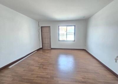 Spacious living room with hardwood flooring and window.