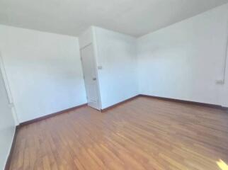 Empty bedroom with hardwood flooring and white walls