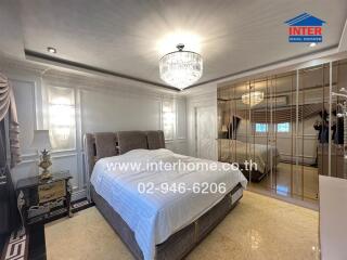 Luxurious bedroom with a large bed, chandelier, built-in mirrored wardrobe, and elegant decor