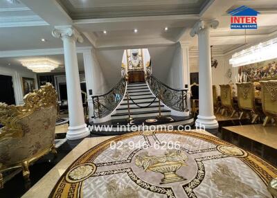 Luxury interior with ornate staircase, dining area, and regal furnishings