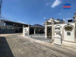 Stylish gated entrance with white columns and decorative urns