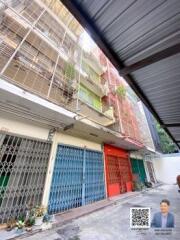 Exterior view of a building with multiple floors and metal grates covering the entrances