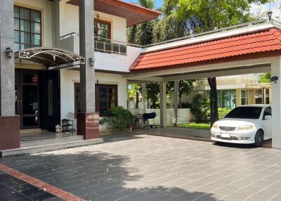 A multi-story house with a tiled roof, a driveway, and a car parked.