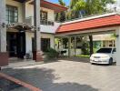 A multi-story house with a tiled roof, a driveway, and a car parked.