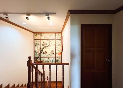 Decorated staircase landing with wooden railing and wall art