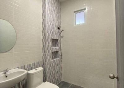 Modern bathroom with tiled walls and flooring, toilet, sink, and shower