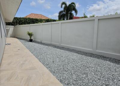 Graveled outdoor space with minimal vegetation and high privacy wall