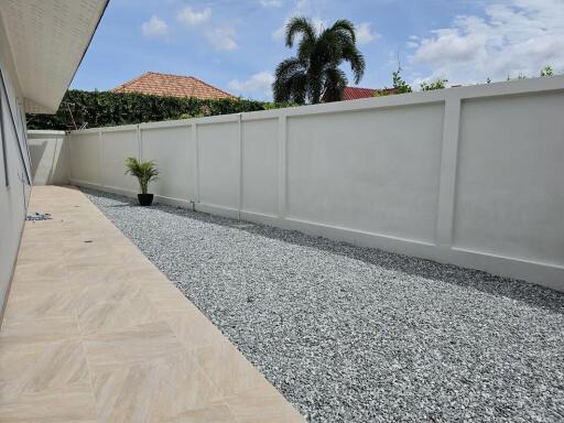 Graveled outdoor space with minimal vegetation and high privacy wall