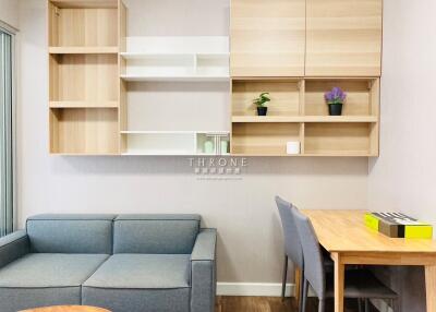 Modern living room with blue sofa, wooden shelving, and dining table