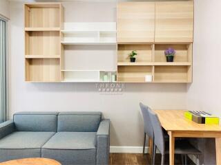 Modern living room with blue sofa, wooden shelving, and dining table