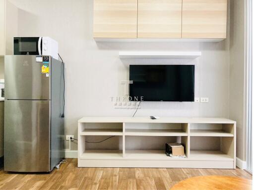 Modern living space with TV, storage unit, and kitchen appliances