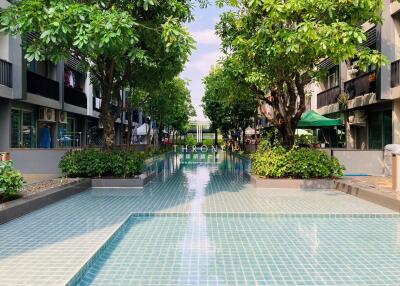 Outdoor pool with green trees and seating area