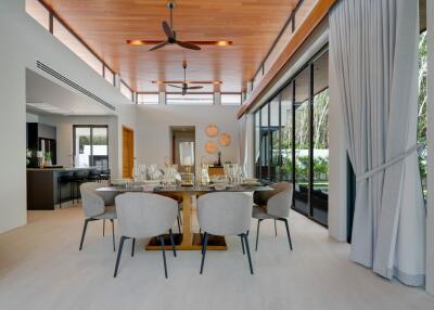 Spacious modern dining area with a stylish wooden ceiling, large windows, and elegant furnishing.