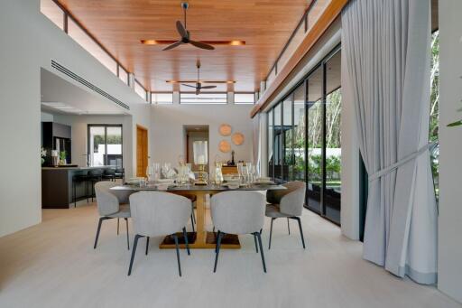 Spacious modern dining area with a stylish wooden ceiling, large windows, and elegant furnishing.