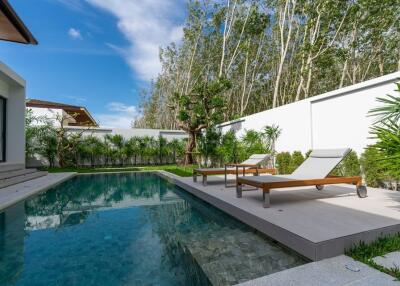 Outdoor pool area with lounge chairs and greenery