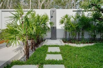 Lush garden area with outdoor shower and pathway