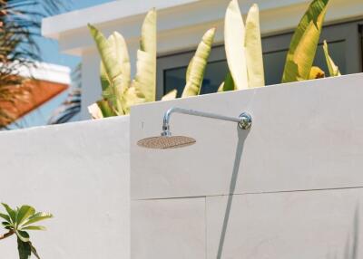 Outdoor shower with plants and building in the background