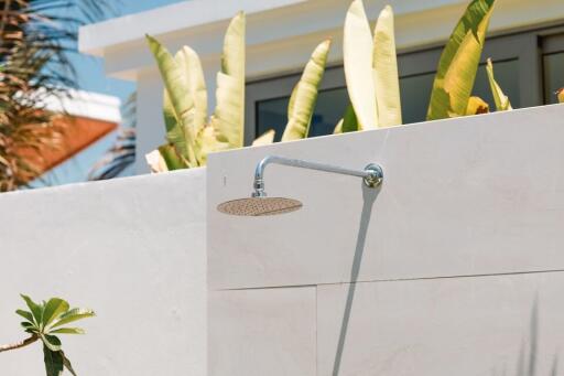 Outdoor shower with plants and building in the background