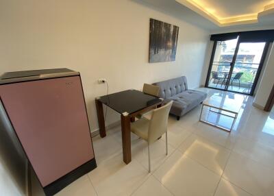 Modern living area with dining table, sofa, refrigerator, and balcony