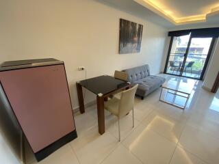 Modern living area with dining table, sofa, refrigerator, and balcony