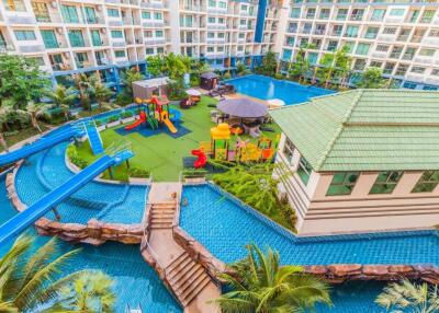 Exterior view of a modern residential building with a swimming pool, water slide, and playground.