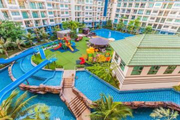 Exterior view of a modern residential building with a swimming pool, water slide, and playground.