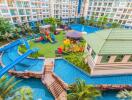 Exterior view of a modern residential building with a swimming pool, water slide, and playground.