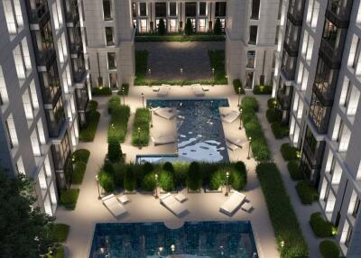 Aerial view of a modern residential complex with a central courtyard featuring pools and greenery