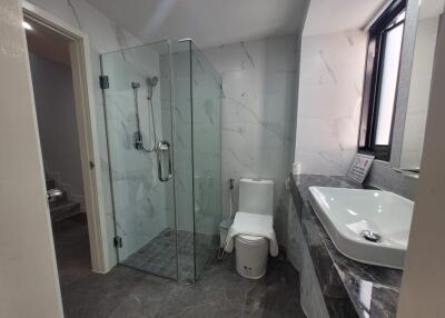 Modern bathroom with glass shower, sink, and toilet