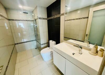 Modern bathroom with a walk-in shower, toilet, and sink with a large mirror