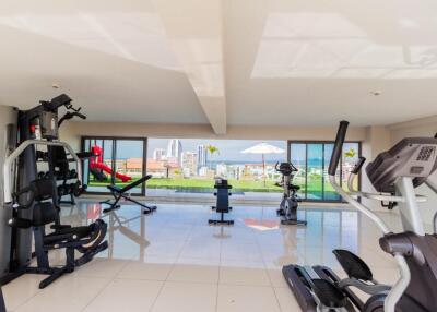 Well-equipped home gym with modern fitness machines and large windows offering a view of the city.