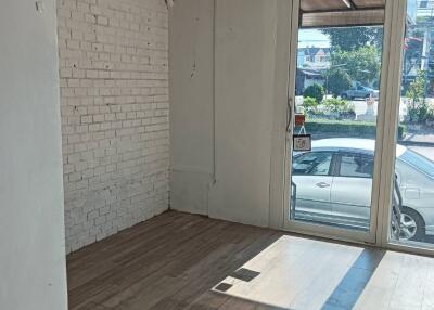 Empty room with brick wall, hardwood floor, and large windows