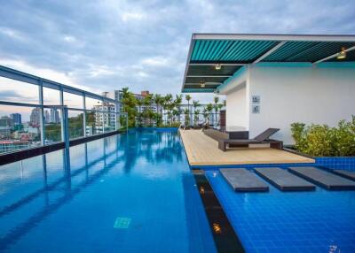 Rooftop pool area with poolside lounge chairs and city view