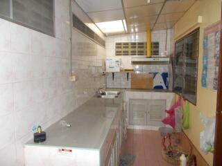 A simple kitchen with metal countertops and tiled walls.