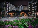 Modern apartment complex at night with well-lit exterior and poolside seating