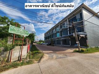 Exterior view of a modern apartment building with a street and greenery