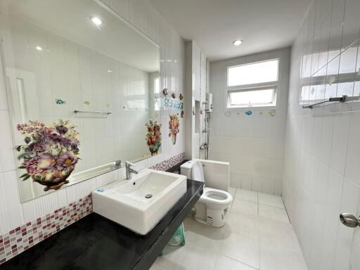 Modern bathroom with large mirror, sink, toilet, and shower