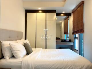 Modern bedroom with a bed, wardrobe, and windows with blinds