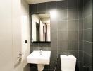 Modern bathroom with dark tiled walls and wooden floor